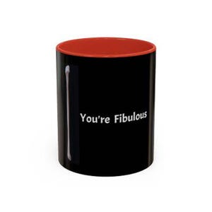 May include: Black coffee mug with a red rim. The mug has white text that says "You're Fibulous" and a white stick figure on the left side.
