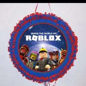 May include: A round piñata with a red and blue fringed border. The center features the text "INSIDE THE WORLD OF ROBLOX" and images of Roblox characters. A fun party decoration.