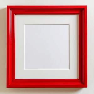 May include: A square red picture frame with a white mat. The frame is a vibrant, glossy red, and the mat is a clean white. The frame is designed to hold a square image.