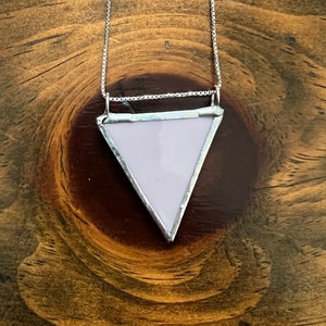 Op de afbeelding: Een zilveren ketting met een lichtpaarse driehoekige hanger.