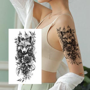 Puede incluir: Tatuaje temporal en blanco y negro con un diseño detallado de zorro y detalles florales. El tatuaje presenta la cara de un zorro rodeada de flores y hojas, creando una estética inspirada en la naturaleza.