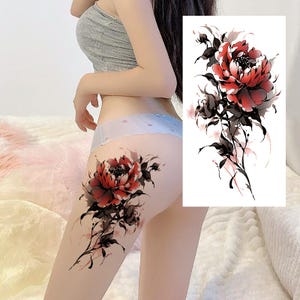 Op de afbeelding: Een tijdelijke tattoo met een grote rode pioenroos met zwarte en grijze bladeren en stelen. Het bloemendesign is gedetailleerd en artistiek, met een aquareleffect. De tattoo is op de dij aangebracht.