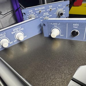 Könnte beinhalten: Drei hellblaue, 3D-gedruckte Cockpit-Bedienfelder für Flugzeuge mit weißen Drehknöpfen, schwarzen Drucktasten und weißen Beschriftungen wie MULTISCANS, GCS, TILT, FLOOD LT, INTEG LT, AIDS und DFDR. Die Paneele verfügen über Befestigungslöcher.