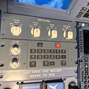 Könnte beinhalten: Nahaufnahme eines Flugzeugcockpit-Bedienfelds. Das Panel ist dunkelgrau mit weißem Text und Knöpfen. Es verfügt über Schalter mit der Aufschrift "ATT HDG", "AIR DATA" und "EIS DMC". Darunter befinden sich Tasten für "ENG", "BLEED" und "PRESS". Der Text "MAX TAKE OFF WEIGHT REFER TO EFB" ist sichtbar.