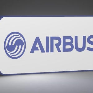 May include: A rectangular sign with rounded corners featuring a white face and a dark blue border. The sign displays the blue Airbus logo on the left side and the word AIRBUS in blue capital letters on the right side of the white surface.