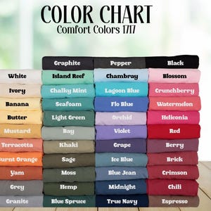 May include: A color chart for Comfort Colors 1717 t-shirts, displaying a large stack of folded shirts in various shades. The text reads COLOR CHART and Comfort Colors 1717, followed by labels for each color including White, Ivory, Banana, Butter, Mustard, Terracotta, Burnt Orange, Yam, Grey, Granite, Graphite, Island Reef, Chalky Mint, Seafoam, Light Green, Bay, Khaki, Sage, Moss, Hemp, Blue Spruce, Pepper, Chambray, Lagoon Blue, Flo Blue, Orchid, Violet, Grape, Ice Blue, Blue Jean, Midnight, True Navy, Black, Blossom, Crunchberry, Watermelon, Heliconia, Red, Berry, Brick, Crimson, Chili, and Espresso.