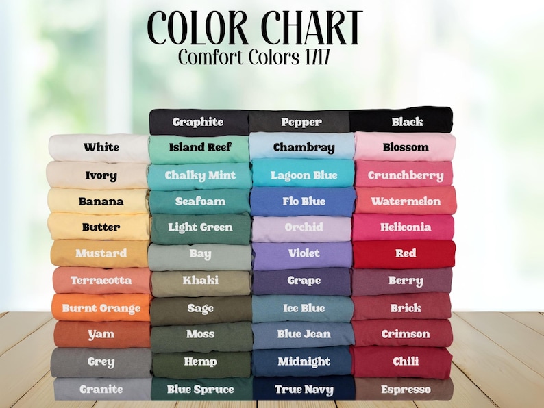 May include: A color chart for Comfort Colors 1717 t-shirts, displaying a large stack of folded shirts in various shades. The text reads COLOR CHART and Comfort Colors 1717, followed by labels for each color including White, Ivory, Banana, Butter, Mustard, Terracotta, Burnt Orange, Yam, Grey, Granite, Graphite, Island Reef, Chalky Mint, Seafoam, Light Green, Bay, Khaki, Sage, Moss, Hemp, Blue Spruce, Pepper, Chambray, Lagoon Blue, Flo Blue, Orchid, Violet, Grape, Ice Blue, Blue Jean, Midnight, True Navy, Black, Blossom, Crunchberry, Watermelon, Heliconia, Red, Berry, Brick, Crimson, Chili, and Espresso.