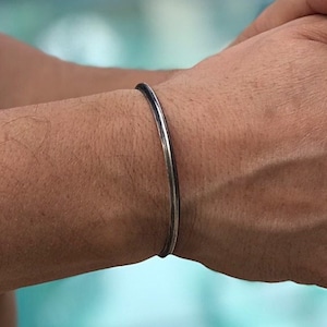 May include: A simple silver bangle bracelet with a polished finish.