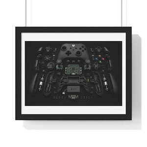 Peut inclure: Une impression encadrée présentant une vue éclatée d'une manette de jeu noire. L'image montre les composants démontés, y compris la coque extérieure, le circuit imprimé interne, les boutons, les joysticks et les moteurs sur fond noir.