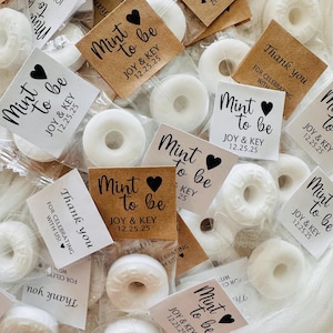 May include: White mint candies in clear packaging, with small tags that read "Mint to be" and "Thank you." The tags are brown and white, with a heart symbol. The text "JOY & KEY 12.25.25" is also printed on the tags.