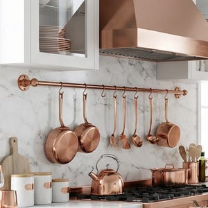 May include: A set of three ceramic mugs with a speckled, matte finish. The mugs are in shades of cream, light brown, and dark brown. Each mug has a simple, minimalist design and a rounded handle. The mugs are likely for coffee or tea.