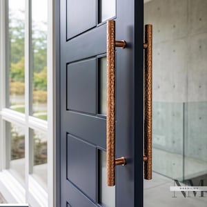 May include: A dark navy blue door featuring a vertical, cylindrical door handle with a textured, hammered copper finish. The door includes rectangular panels and vertical glass inserts. The handle is mounted on both sides of the door.