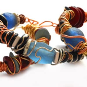 以下が含まれることがあります： ボヘミアンスタイルの手作りブレスレット3本。各ブレスレットは、ターコイズ、ブルー、レッド、ブラックなど、さまざまな色のビーズを組み合わせており、銅線で包まれています。ブレスレットは白い背景に表示されています。