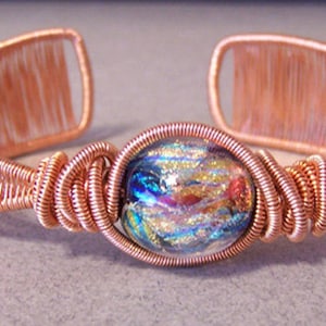 Puede incluir: Pulsera de pu&ntilde;o de alambre de cobre con una cuenta de vidrio dicroico. La pulsera presenta un dise&ntilde;o de alambre tejido con una cuenta de vidrio colorida en el centro. El dise&ntilde;o de pu&ntilde;o abierto permite un f&aacute;cil uso.