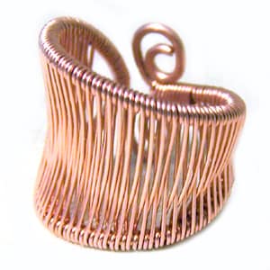 May include: A copper-colored wire ring with a unique, open design. The ring features vertical wire strands held together by a coiled top and bottom. A decorative swirl detail is on the side. The ring is a piece of handmade jewelry.