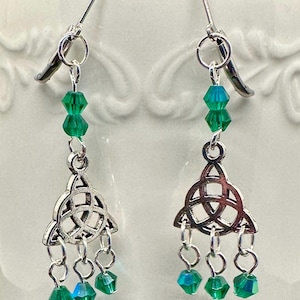 May include: Silver-toned Celtic knot earrings with green and teal faceted beads. The earrings feature a dangling design with three smaller beads below the Celtic knot. The ear wires are silver-toned.