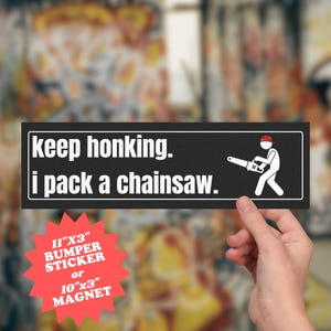 Może przedstawiać: Czarna naklejka na zderzak z białym tekstem: "keep honking. i pack a chainsaw." Po prawej stronie znajduje się ludzik z piłą łańcuchową. Naklejka ma wymiary 28 cm x 8 cm.