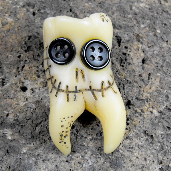 Smiling molar monster. Human teeth brooch with two roots and two buttons in his eyes