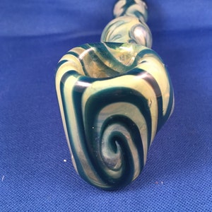 May include: A glass pipe with a swirl design in shades of green and white.