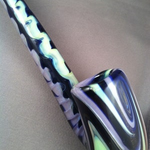 Pode incluir: Um cachimbo de vidro com um padrão de redemoinho de azul, branco e verde. O cachimbo tem a forma de um cachimbo tradicional com um caule longo e uma tigela.