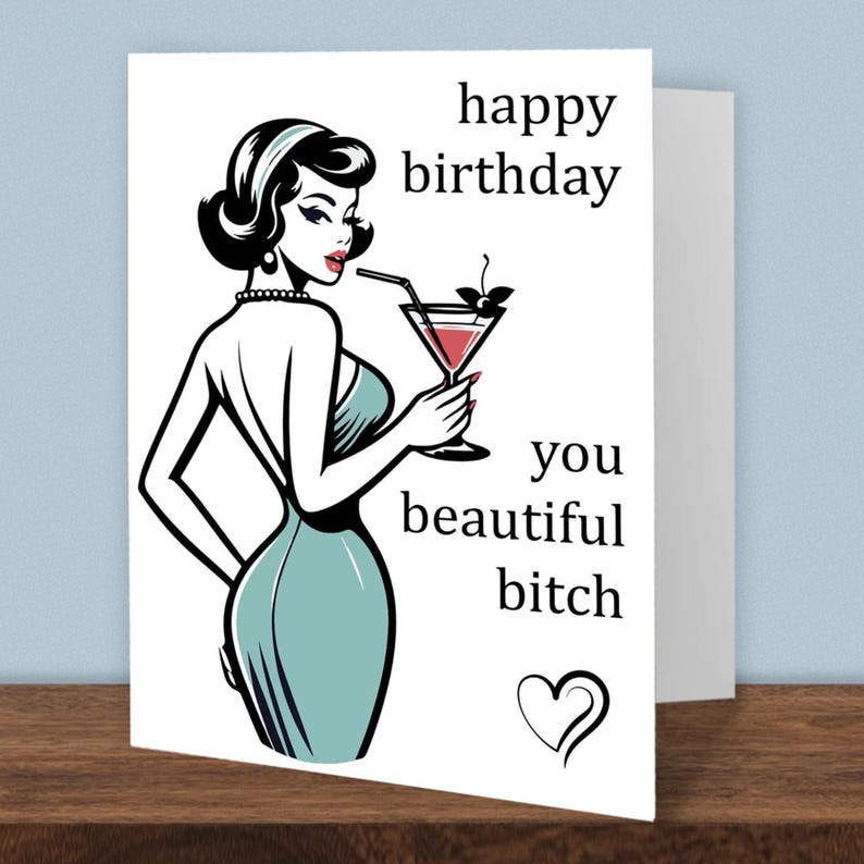 Puede incluir: Tarjeta de cumplea&ntilde;os con una ilustraci&oacute;n retro de una mujer con un vestido color turquesa sosteniendo un c&oacute;ctel. La tarjeta dice "feliz cumplea&ntilde;os, hermosa perra" con un s&iacute;mbolo de coraz&oacute;n. La tarjeta est&aacute; sobre una superficie de madera.