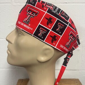 May include: A red and black Texas Tech University scrub cap. The cap features a repeating pattern of the Texas Tech logo, the letter "T", and a silhouette of a cowboy hat. The words "Texas Tech University" are printed on the cap.