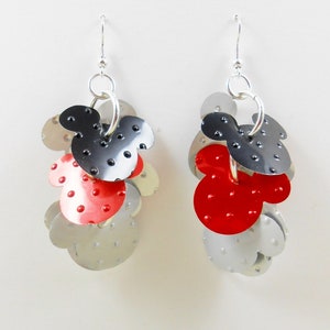 Puede incluir: Pendientes hechos a mano con un dise&ntilde;o de Mickey Mouse. Los pendientes son de metal plateado con detalles en rojo y negro. Cuelgan de ganchos plateados. El texto "JMP Designs Danville, CA" es visible.