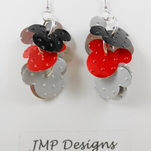 Puede incluir: Pendientes colgantes con dise&ntilde;o de cabeza de Mickey Mouse en metal rojo, negro y plateado. Los pendientes tienen cierre de poste. El texto "JMP Designs Danville, CA" es visible. Un accesorio divertido.