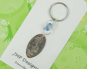 May include: A silver-colored keychain with a pressed penny featuring a house and balloons design. The keychain includes a blue bead and a silver ring. The text "JMP Designs Danville" is visible on the card.