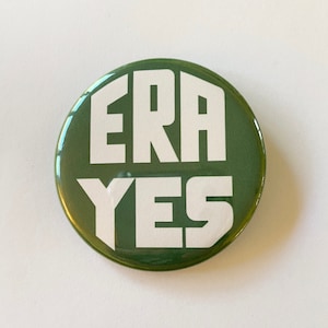 May include: A round, green button with the white text "ERA YES" in a bold, sans-serif font. The button has a glossy finish and a simple, direct design, suitable for political or social activism.