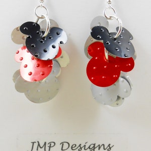 Puede incluir: Pendientes colgantes con un dise&ntilde;o en capas de Mickey Mouse. Los pendientes presentan elementos met&aacute;licos rojos, negros y plateados con un acabado texturizado y punteado. Cuelgan de ganchos plateados.