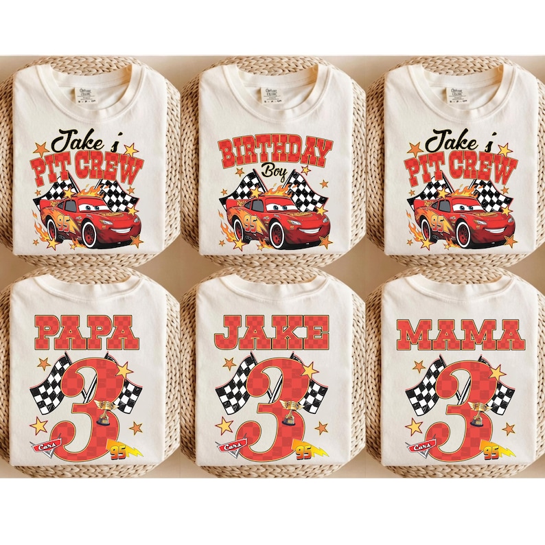 Puede incluir: Seis camisetas de color blanco roto con gr&aacute;ficos de coches de carreras rojos con el n&uacute;mero 95, banderas a cuadros y estrellas. Tres camisetas muestran 'Jake's Pit Crew' o 'Birthday Boy', y tres muestran 'PAPA', 'JAKE' o 'MAMA' con un n&uacute;mero 3 grande.