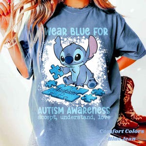 K&ouml;nnte beinhalten: Blaues Comfort Colors T-Shirt mit einer Grafik von Stitch, der Puzzleteile h&auml;lt. Das Shirt tr&auml;gt den Text "Wear BLUE FOR Autism Awareness" und "accept, understand, love".