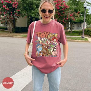 Puede incluir: Camiseta de color carmes&iacute; con la inscripci&oacute;n "Toy Story" y un gr&aacute;fico de personajes de la pel&iacute;cula de animaci&oacute;n. El dise&ntilde;o incluye a Buzz Lightyear, Woody, Jessie y otros personajes. La camiseta es de manga corta y cuello redondo.