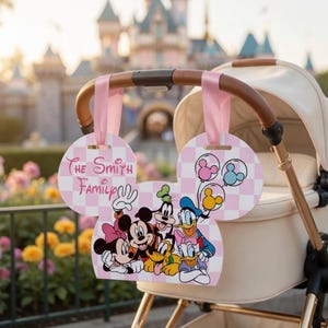 May include: A stroller sign shaped like Mickey Mouse ears with a pink and white checkered pattern. It features a group illustration of Minnie Mouse, Mickey Mouse, Goofy, Pluto, Donald Duck, and Daisy Duck, with the text The Smith Family.