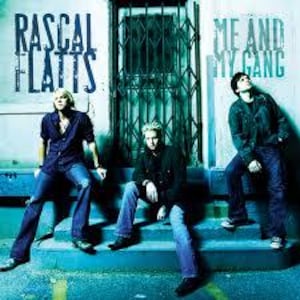 Può includere: Un'immagine promozionale per il gruppo musicale country Rascal Flatts. La copertina dell'album presenta i membri della band in piedi su una serie di gradini di fronte a un edificio blu e bianco. Il titolo dell'album "Me and My Gang" è visualizzato in grandi lettere bianche sul lato destro dell'immagine.