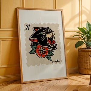 May include: Framed art print with a black panther tattoo design and a red and orange flower. The artwork is on a beige background with the number "21" and the word "panther". The print is in a wooden frame.