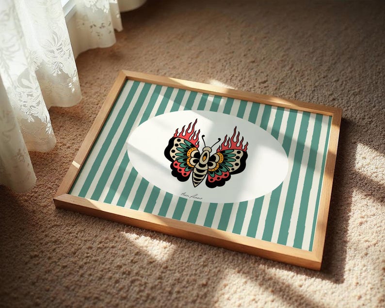 May include: Framed art print with a butterfly design, flames, and teal stripes. The artwork is in a wooden frame. The butterfly is in an oval shape. The artwork is in a wooden frame.