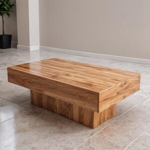 May include: A rectangular wooden coffee table with a natural wood grain finish. The table has a thick, boxy top and a solid base. The dimensions are approximately 122 cm long, 61 cm wide, and 41 cm high.