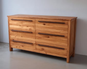 May include: A six-drawer dresser made of light wood with dark brown metal drawer pulls.