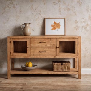 Może przedstawiać: Jasnobrązowy drewniany kredens z dwiema szufladami i dwiema szafkami ze szklanymi drzwiami. Na kredensie znajduje się oprawiony obraz liścia klonu, ceramiczny dzbanek, miska z owocami i wiklinowy kosz.