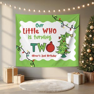 May include: A green and white rectangular fabric banner featuring the text Our Little WHO is turning TWO and Oliver's 2nd Birthday. The design includes a stylized green Christmas tree, a red ornament, and black string light graphics.
