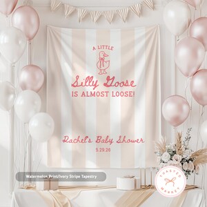 Pu&ograve; includere: Un fondale per baby shower con un design a righe rosa e avorio. Il testo recita "A Little Silly Goose Is Almost Loose!" e "Rachel's Baby Shower 5.29.26". Palloncini bianchi e rosa circondano lo sfondo.