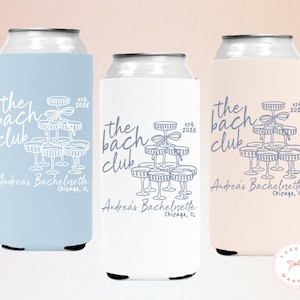 May include: Three can coolers in pastel colors: light blue, white, and pale peach. Each cooler features the text "the bach club" with a champagne tower graphic and "est 2025". The text "Andrea's Bachelorette, Chicago, IL" is also included.