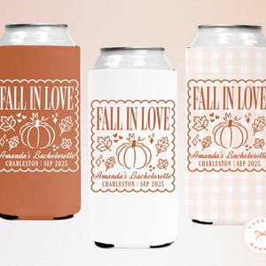 May include: Three can coolers with a fall theme. Each cooler features the text "FALL IN LOVE" with a pumpkin and leaf design. The coolers are in shades of orange, white, and a light pink gingham pattern. Text at the bottom reads "Amanda's Bachelorette Charleston | SEP 2025."
