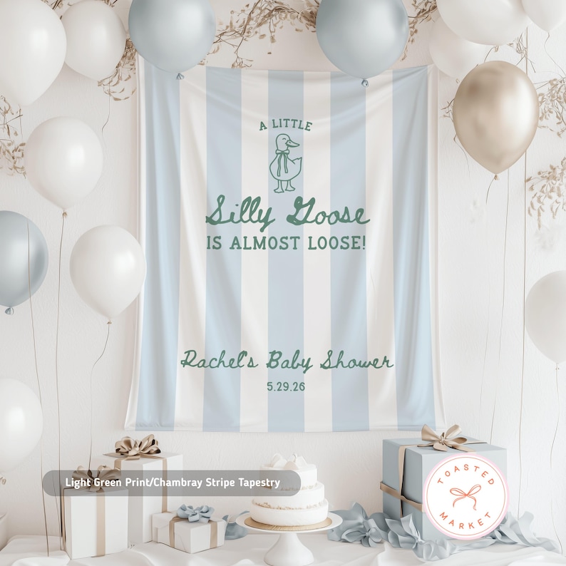 Pu&ograve; includere: Un arazzo a righe verde chiaro e bianco con il testo "A Little Silly Goose Is Almost Loose!" e "Rachel's Baby Shower 5.29.26". La scena comprende palloncini bianchi e argentati, regali e una torta, suggerendo un tema baby shower.