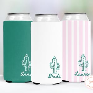 May include: Three can coolers in teal, white, and pink with a cactus design. The teal cooler has the name "Anna" in script, the white cooler says "Bride", and the pink striped cooler says "Lauren".