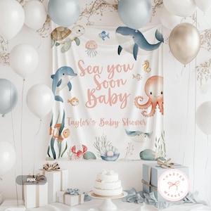 Puede incluir: Un tel&oacute;n de fondo para baby shower con tem&aacute;tica marina. La pancarta blanca presenta ilustraciones de acuarela de vida marina, incluyendo una ballena, un delf&iacute;n y un pulpo. El texto dice "Sea you Soon Baby" y "Taylor's Baby Shower". Globos y regalos rodean la pancarta.