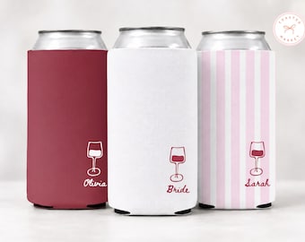 May include: Three cylindrical beverage insulators featuring a wine glass graphic and custom text. One is solid maroon with the name Olivia, one is solid white with the word Bride, and one has vertical pink and white stripes with the name Sarah.