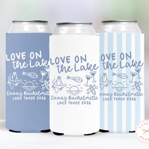 May include: Three can coolers in blue, white, and blue striped patterns. Each cooler features the text "LOVE ON the Lake" and "Emma's Bachelorette LAKE TAHOE 2026" with lake-themed illustrations.
